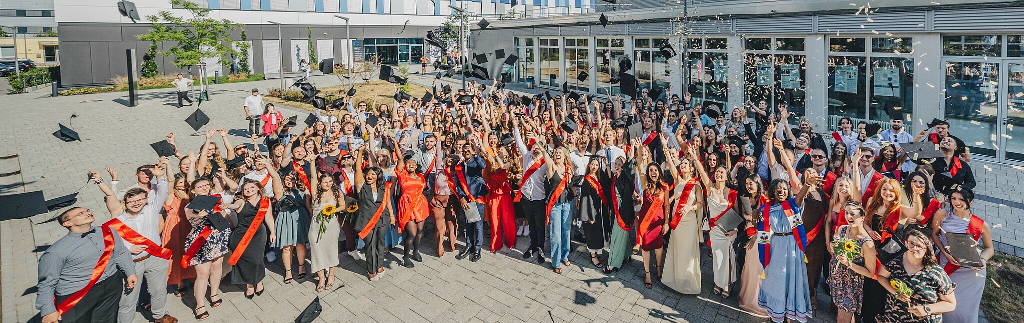 Absolvent*innen werfen ihre Abschlusshüte
