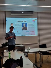 Lecture by the founding office: Young man in front of a PowerPoint presentation