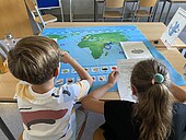 Rückenansicht von zwei Kindern, die eine Weltkarte betrachten