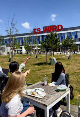  Drei Frauen beim Mittagessen zeigen gemeinsam auf den Schriftzug "Es wird"