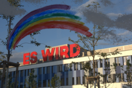 C-Gebäude mit dem Schriftzug "Es wird", darüber ist ein gemalter Regenbogen zu sehen