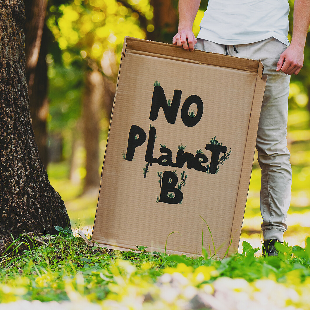 Pappschild mit Aufschrift No Planet B vor grünem Hintergrund