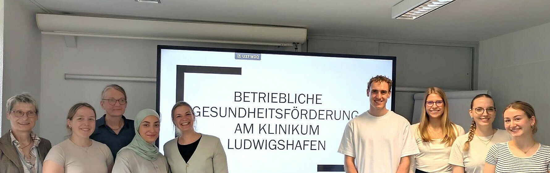 Personengruppe vor großem Präsentationsbildschirm