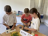 Drei Kinder beim der Butter-Herstellung